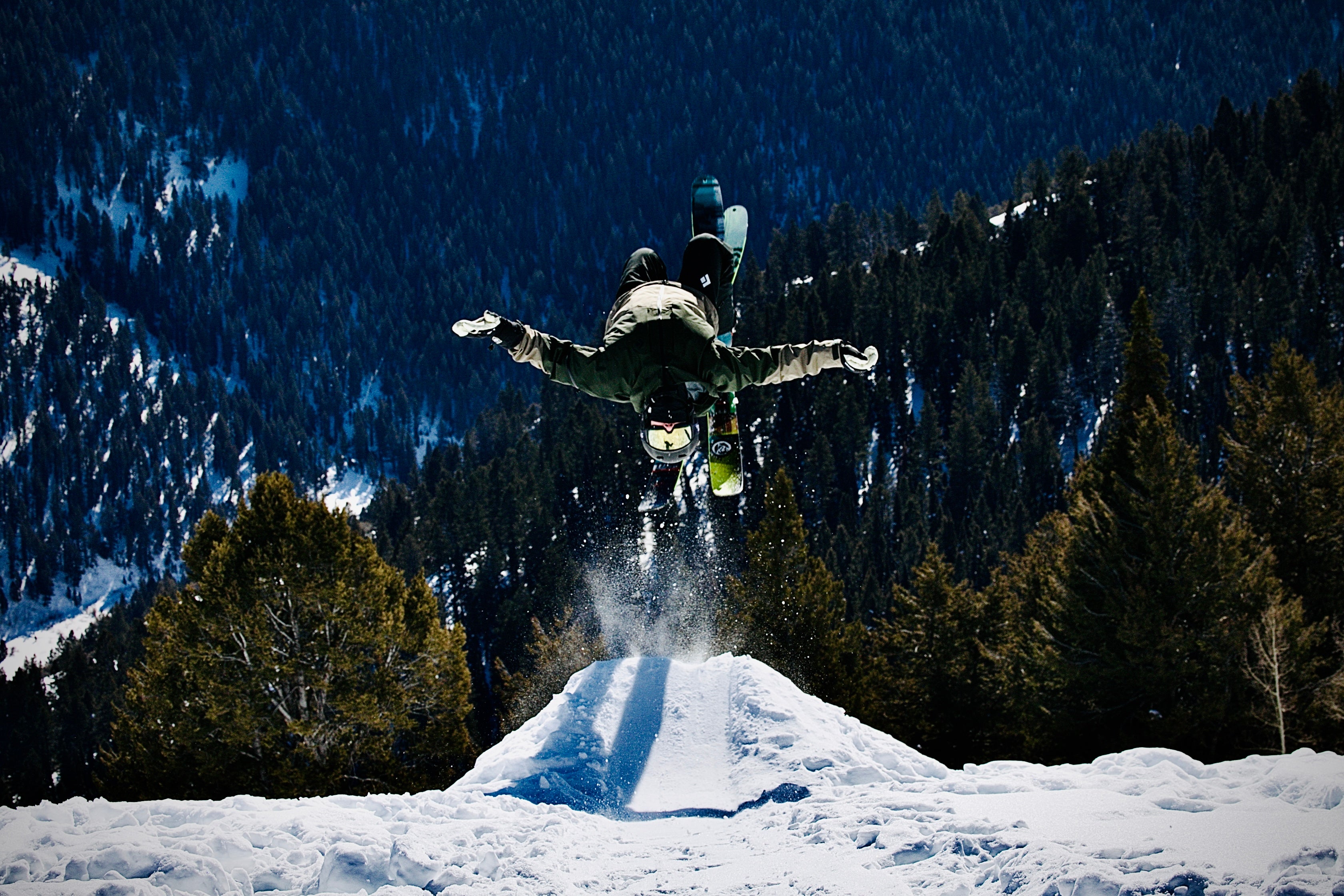 skier doing a back flip on a snowy mountain side